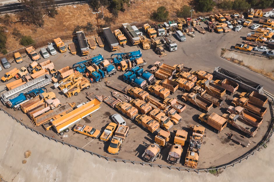 Drone shot of a parking lot filled with industrial vehicles, showcasing an organized layout from above.
